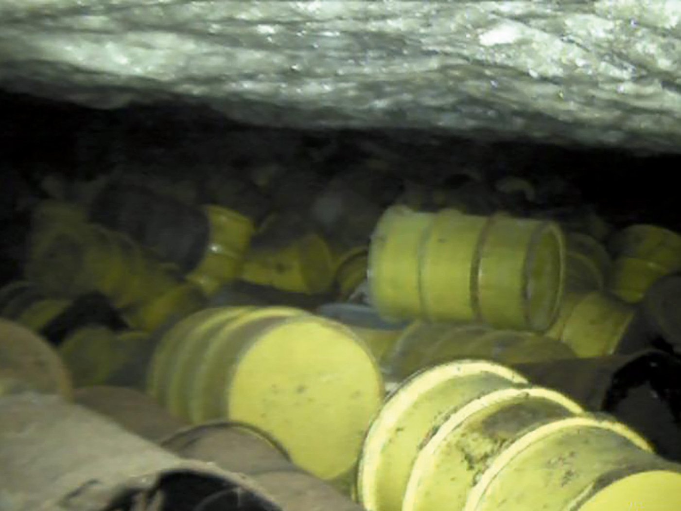 Mehrere gelbe Fässer liegen in einem Hohlraum unter Tage