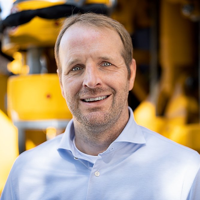 Ein Mann mit kurzen blonden Haaren und Drei-Tage-Bart lächelt in die Kamera.