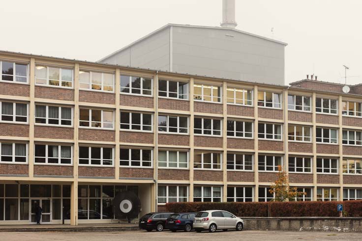 Gebäude mit Parkplatz, eine große Halle im Hintergrund