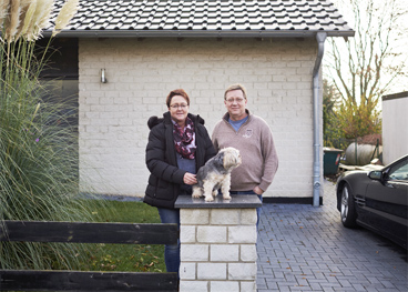 Elke Köchy und Thomas Mertens mit einem Hund vor einem Wohnhaus