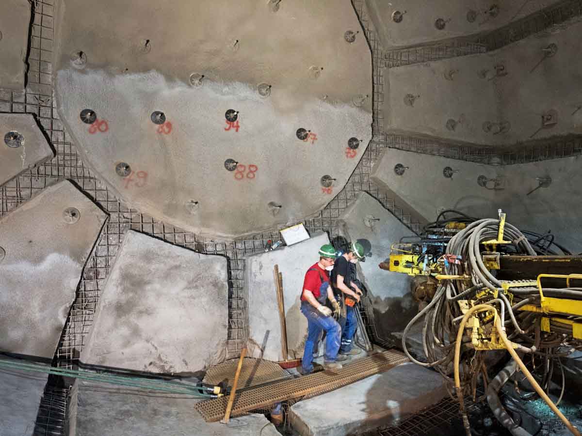 Arbeiter mit Gerät vor einer Tunnelwand mit roten Markierungen