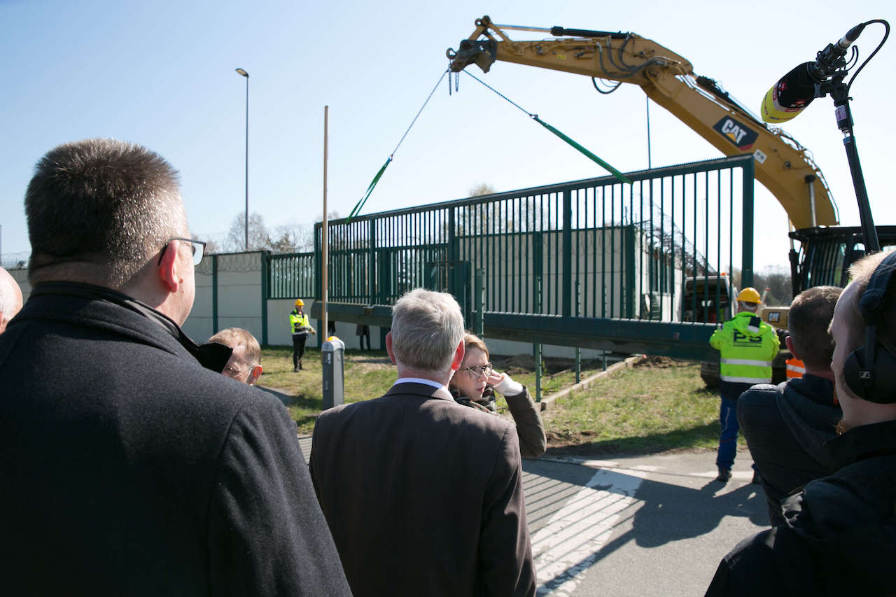 Ein Bagger demontiert ein Gatter in einem Zaun