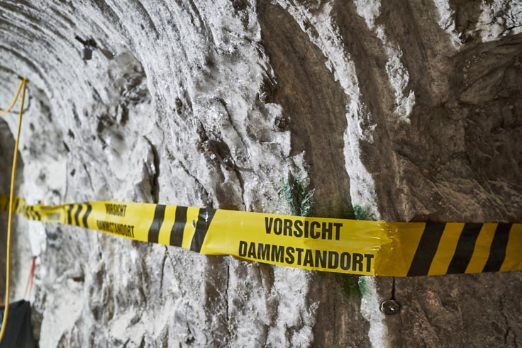 Absperrband mit Aufschrift "Vorsicht Dammstandort" vor der Grubenwand