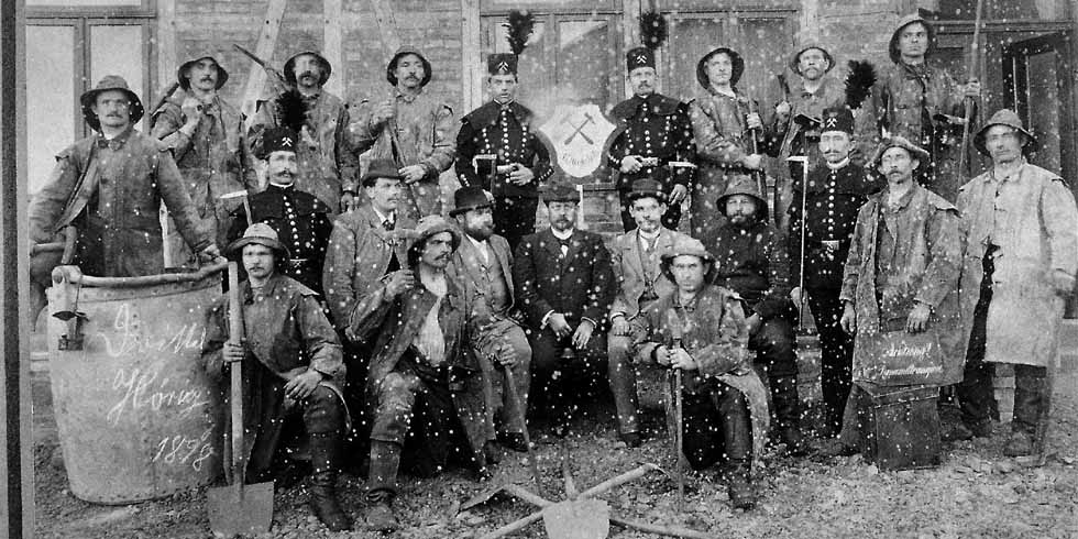 Ein historisches Bild von einer Gruppe Männern mit Schaufeln, Hacken, Kübeln und Sprengstoff