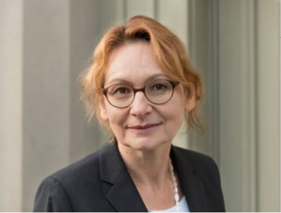 Porträtbild von Dr. Anne Eckhardt. Das Foto zeigt eine Frau in einem dunklen Blazer, halblangen rotblonden Haaren und einer Brille mit runden Fassungen.